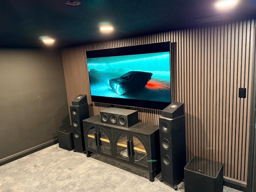 Custom home theater with wall-mounted TV, surround speakers, and media console